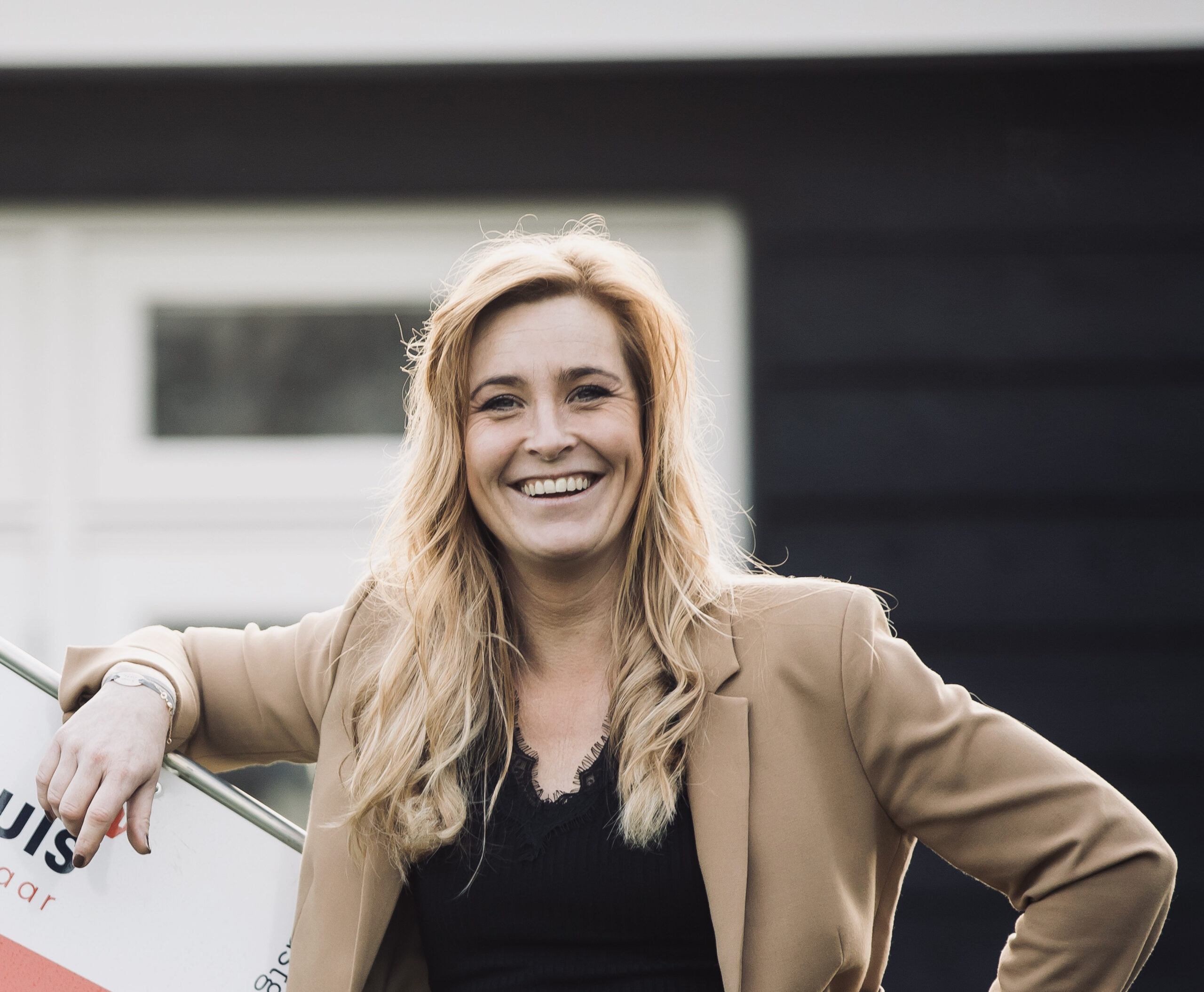 Sanne Nieuwenhuis bij een 'te koop'-bord van Nieuwenhuis als een van de makelaars Wierden.