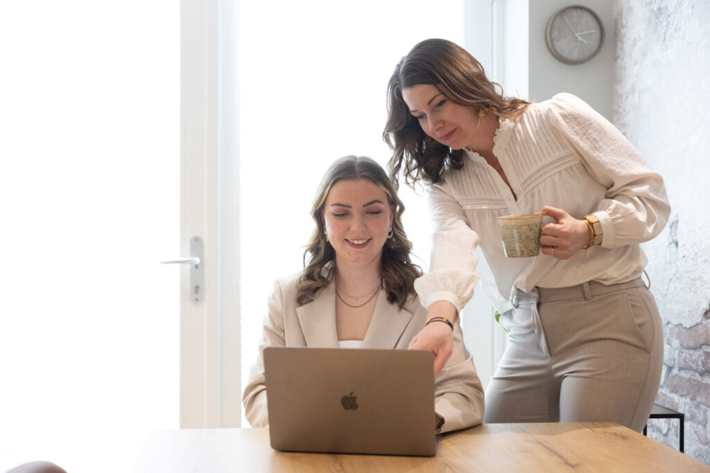Makelaar van Nieuwenhuis bespreekt woningverkoop met klant aan tafel met laptop