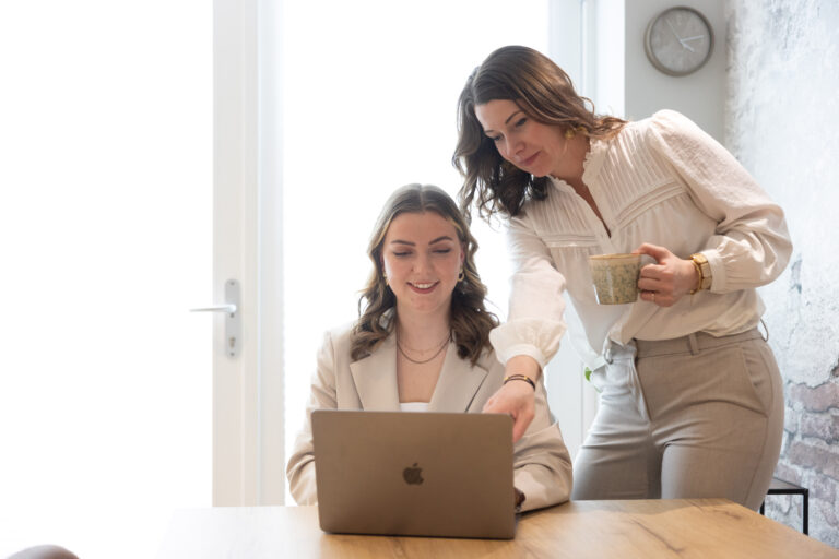Makelaar van Nieuwenhuis bespreekt woningverkoop met klant aan tafel met laptop